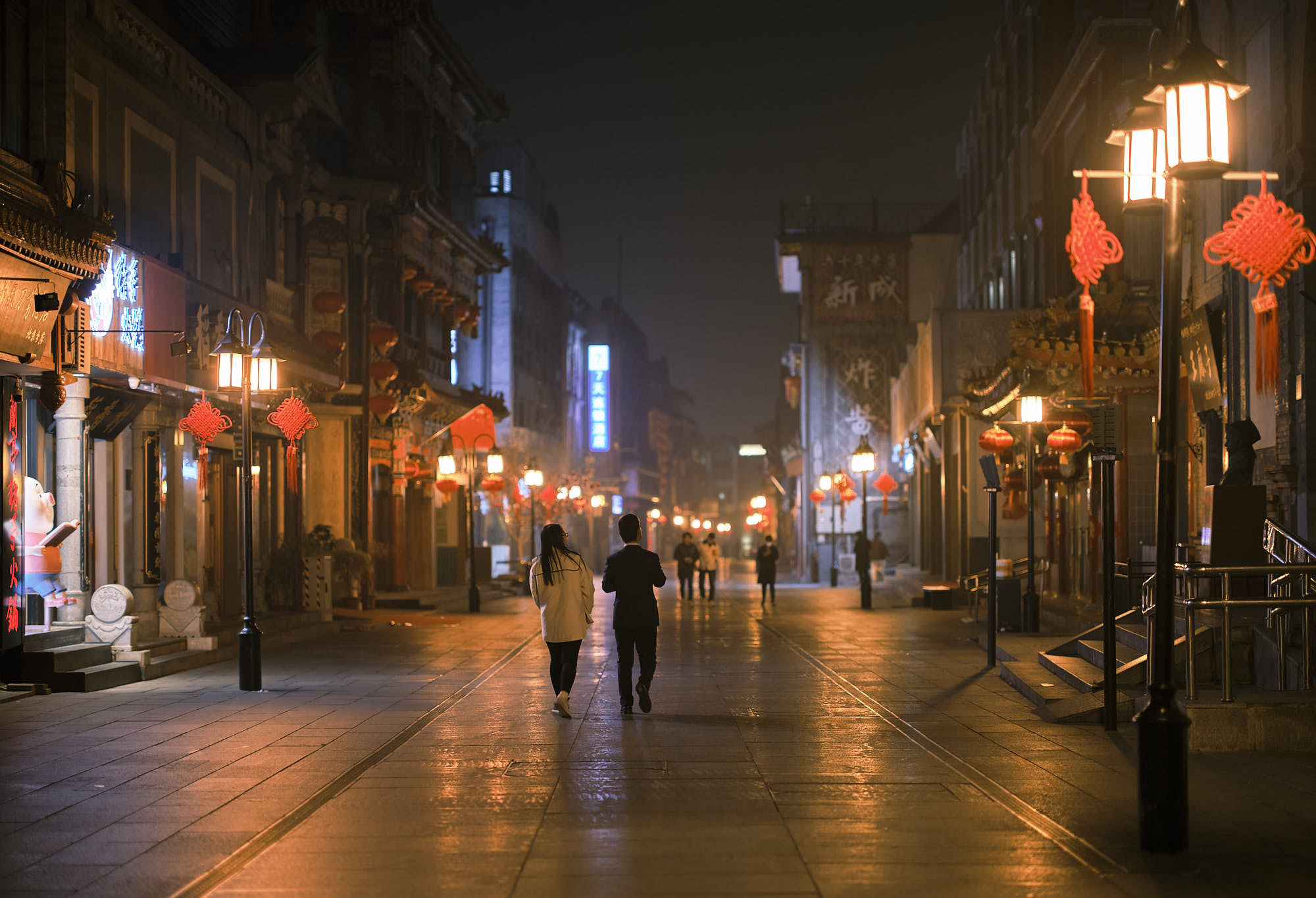 Woman and man walking in the rain in Beijing Qianmen