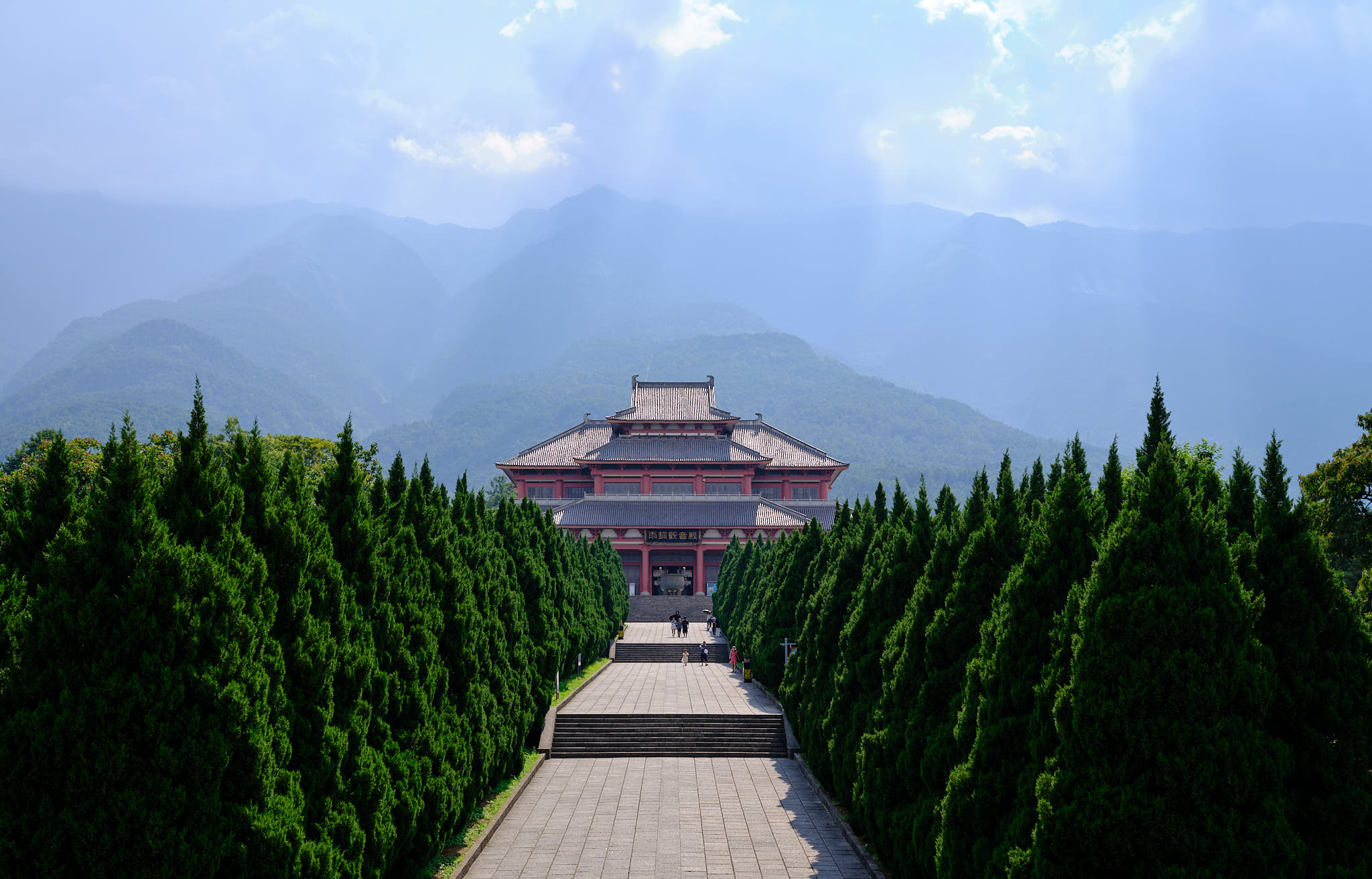 Cangshan Mountain temple with tunnel of trees and mountains in the back
