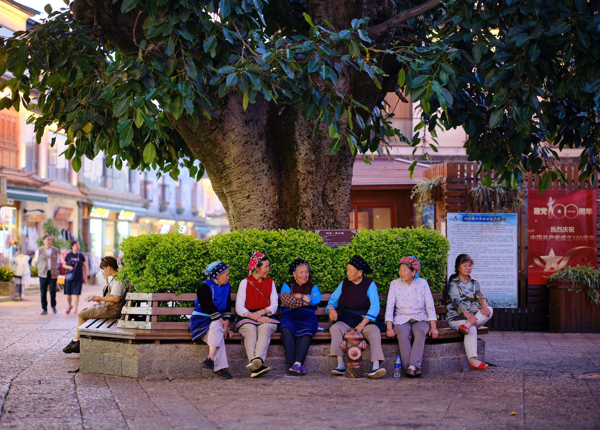 Local ethnic minorities ladies hanging out under a tree in central square Shuanglang